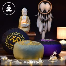 Meditationskissen vor einer Kulisse aus einem Taumfänger und einem Kerzenhalter als Buddddha Statue
